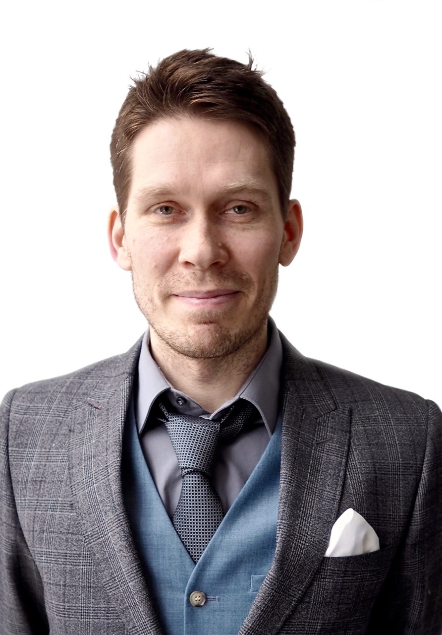 Porträt Jakob Jochmann mit kurzen Haaren leicht lächelnd im Anzug und mit Krawatte
